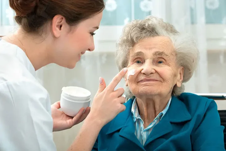 caregiver appliying face cream to elderly lady